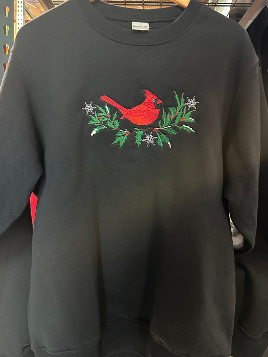 Black sweatshirt with a red cardinal and greenery design on a hanger.